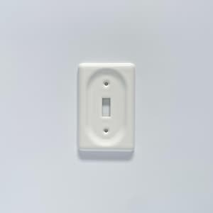 May include: White ceramic light switch cover plate with a single switch opening.