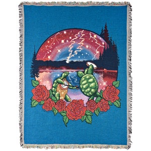 May include: A blue woven tapestry featuring two green turtles playing musical instruments in front of a red, pink, and purple starry sky with a lightning bolt. The turtles are surrounded by red roses.