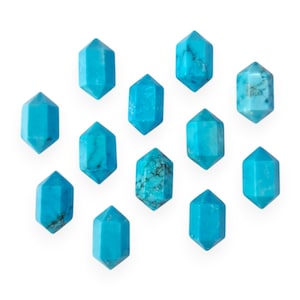 May include: Twelve turquoise gemstone points arranged in a scattered pattern on a white background.