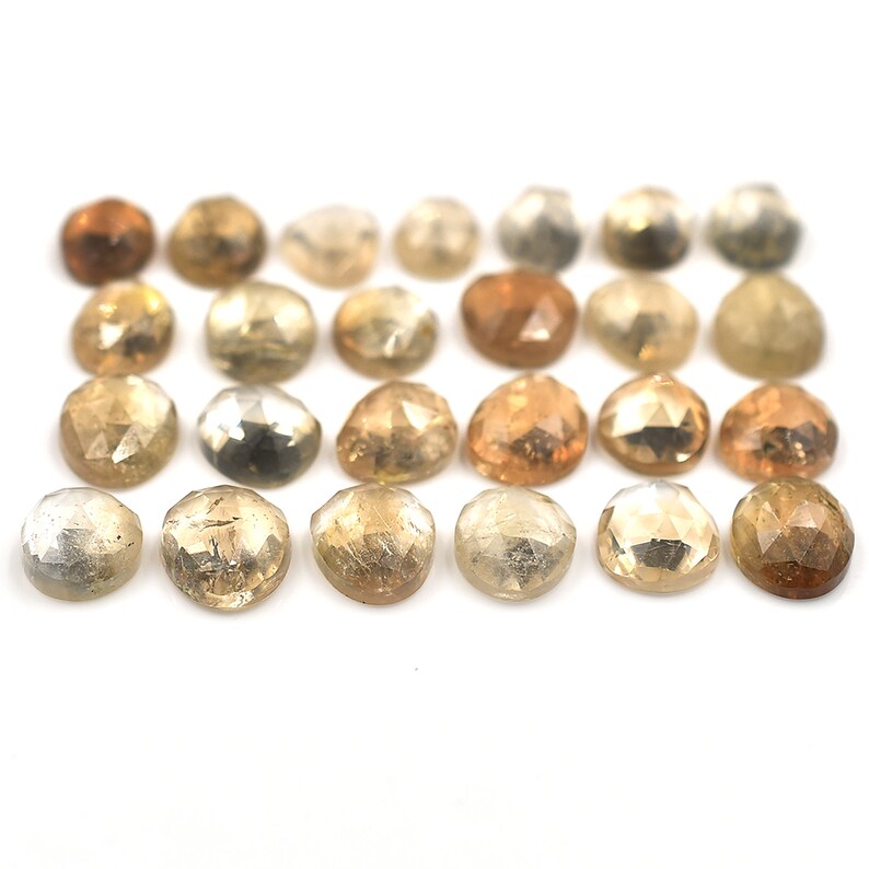 May include: Assortment of 20 faceted, round, natural gemstones in shades of brown, yellow, and white. The stones are approximately 5mm in diameter.