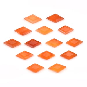 Puede incluir: Quince gemas de color naranja en forma de diamante están dispuestas sobre una superficie blanca. Las gemas varían en tonalidad, desde el naranja claro hasta un naranja rojizo oscuro. Cada piedra tiene un cuadrado incrustado dentro del diamante.