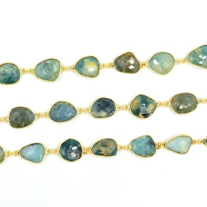 May include: A strand of gold chain with aqua blue gemstone beads. The beads are irregularly shaped and have a rough, natural texture.