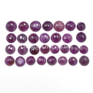 Può includere: Ventiquattro cabochon di pietra preziosa viola sfaccettati. I cabochon sono rotondi e hanno una finitura liscia e lucida.