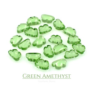 Può includere: Una collezione di pietre preziose di ametista verde a forma di nuvola. Le pietre preziose sono traslucide e hanno un colore verde chiaro. Il testo "GREEN AMETHYST Synthetic Stone" è stampato sotto le pietre preziose.