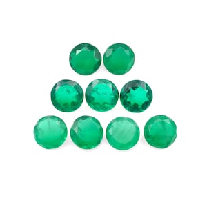 May include: Eight round, faceted, green gemstones arranged in a pyramid shape. The gemstones are smooth and shiny.