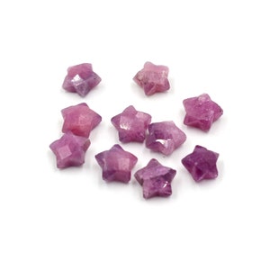 May include: A collection of ten pink star-shaped gemstone beads. The beads are faceted and have a shiny, polished finish.