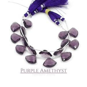 Könnte beinhalten: Eine Strähne aus violetten Amethyst-Edelsteinkugeln, jede Kugel ist facettiert und tropfenförmig. Die Kugeln sind auf einem Silberdraht aufgefädelt und durch kleine silberne Abstandshalter getrennt. Die Kugeln sind kreisförmig angeordnet, die Enden der Strähne sind mit einem violetten Quasten zusammen gebunden.