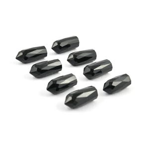 May include: A collection of eight small, black, faceted beads shaped like elongated points or crystals. Each bead features multiple flat surfaces that reflect light, creating a polished appearance. The beads are arranged in a loose cluster.