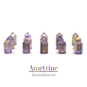 Puede incluir: Una colección de 10 puntas de cristal de ametrina, cada una con una mezcla única de tonos morados y dorados. Las puntas están dispuestas en una fila sobre un fondo blanco. La ametrina es una variedad rara de cuarzo que combina las propiedades de la amatista y el citrino.