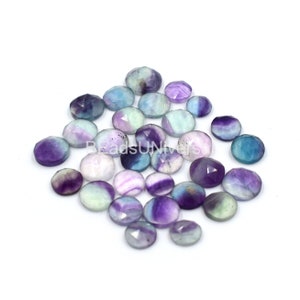 May include: A collection of 20 faceted fluorite gemstone cabochons in shades of purple, blue, and green. The cabochons are approximately 10mm in diameter and have a smooth, polished finish.
