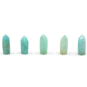 Puede incluir: Cinco puntas de cristal verde azulado dispuestas en fila sobre un fondo blanco.