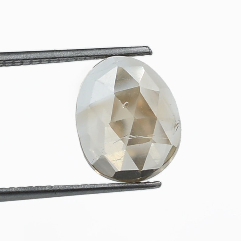 May include: A light brown, oval-shaped, faceted diamond held by tweezers.