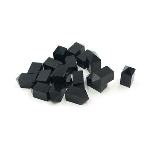 May include: A group of black, faceted, crystal beads. The beads are shaped like small pyramids with a square base.