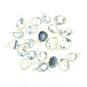 May include: A collection of dendritic opal gemstone pendants with silver-colored metal settings. The opals feature a white base with black and gray dendritic inclusions. The pendants are various shapes, including teardrop, oval, and irregular forms.