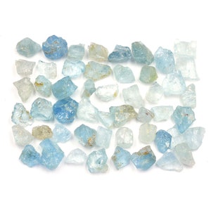 May include: A collection of raw aquamarine crystals in various sizes and shades of blue. The crystals are rough and have a natural, unpolished appearance.