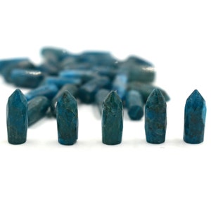 Może przedstawiać: Pięć turkusowych kryształowych punktów ułożonych w rzędzie na białym tle. Punkty są mniej więcej tej samej wielkości i kształtu, z ostrym końcem i płaską podstawą.