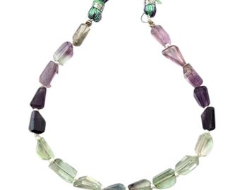 May include: A strand of faceted fluorite beads in shades of green, purple, and lavender. The beads are strung on a white cord and finished with green and purple tassels.