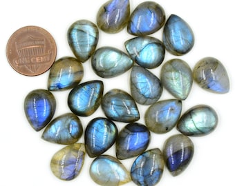 May include: A collection of twenty-one teardrop-shaped labradorite gemstones with iridescent blue and grey flashes, arranged alongside a copper one-cent coin for scale, showcasing smooth, polished surfaces and natural internal fractures.