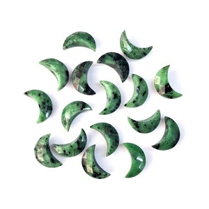 May include: A collection of fifteen crescent moon-shaped gemstones, each featuring a faceted surface. The stones are primarily green with dark black and deep forest green speckled inclusions throughout, creating a varied, natural mineral pattern.
