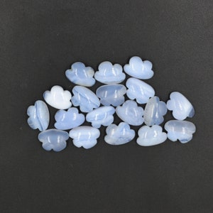 Könnte beinhalten: Eine Sammlung von 17 hellblauen, wolkenförmigen Chalcedon-Cabochons. Die Cabochons sind glatt und poliert und haben eine leicht durchscheinende Optik.