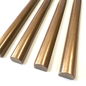 May include: Four gold-colored ceramic tiles with rounded edges. The tiles are arranged in a row, with the ends of each tile slightly overlapping the next.