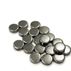 May include: A group of round, silver-colored metal discs. The discs are arranged in a loose pile, with some overlapping.