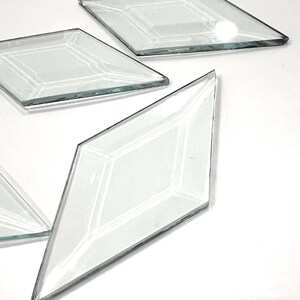 May include: Five clear glass diamond-shaped tiles. The tiles are smooth and have a slight bevel around the edges.