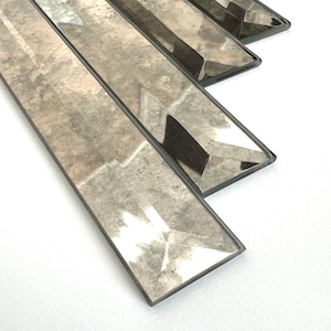 May include: A set of four rectangular, beveled glass tiles with a distressed, antique silver finish. The tiles are arranged in a staggered pattern, with the largest tile at the bottom and the smallest tile at the top.