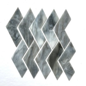 May include: A pattern of gray and white chevron-shaped glass tiles arranged in a herringbone pattern.