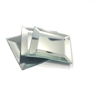May include: Three square beveled mirror tiles, stacked on top of each other. The tiles are clear and reflective.