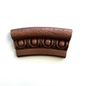 May include: A copper-colored decorative molding with a textured surface and a repeating pattern of rounded shapes.