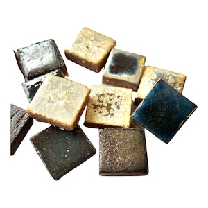 May include: A collection of small, square ceramic tiles in various shades of blue, brown, and white with a speckled glaze. The tiles have a rustic, handmade look.