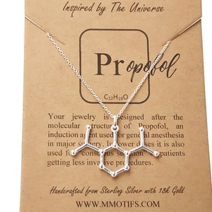 May include: A silver-colored necklace featuring a pendant shaped like the molecular structure of Propofol, displayed on a tan card with the text Molecular Motifs, Propofol, C12H18O, and descriptive text about the chemical compound.