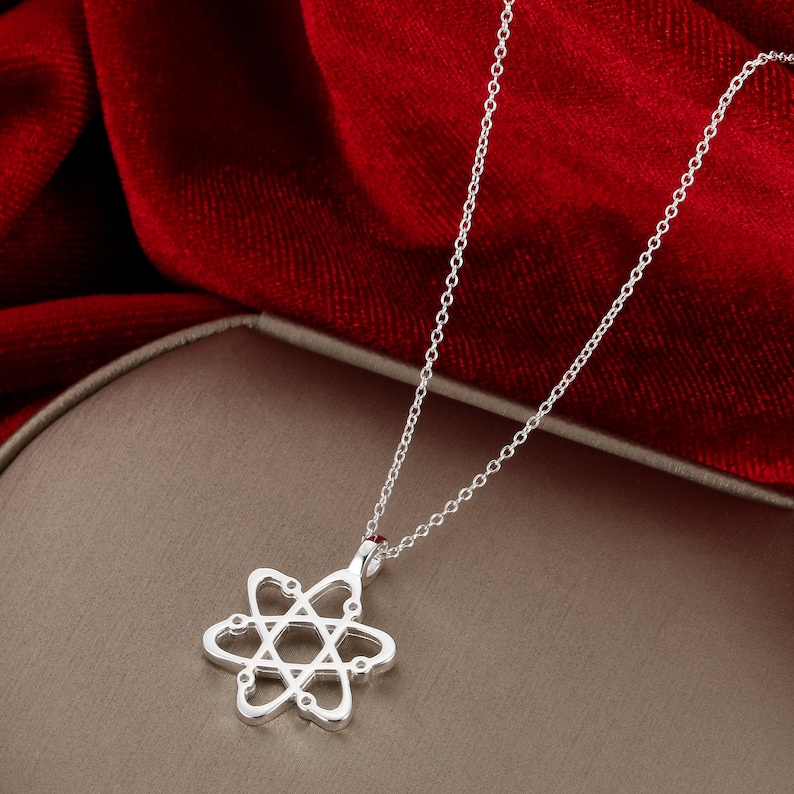 May include: A silver necklace with a delicate atom pendant. The pendant is made of a thin, openwork design with small circles representing electrons.