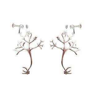 May include: A pair of silver-colored clip-on earrings. Each earring is shaped like a stylized tree or neuron, with a central stem and branching arms. The clip-on mechanism is visible at the top.