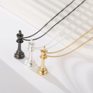 May include: Three gold, silver and black chess king pendant necklaces. Each pendant is a detailed replica of a chess king piece.