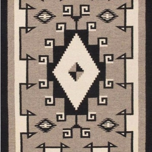 Può includere: Un tappeto Navajo con un motivo geometrico in tonalità di nero, bianco e grigio. Il tappeto presenta una grande forma a diamante al centro, circondata da diamanti e quadrati più piccoli.