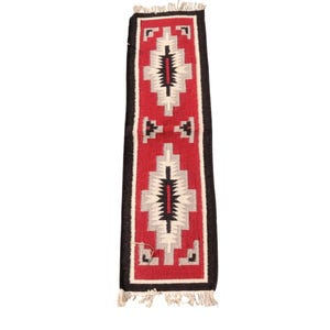 May include: A red, black and white woven rug with a geometric pattern. The rug has fringe on the ends.
