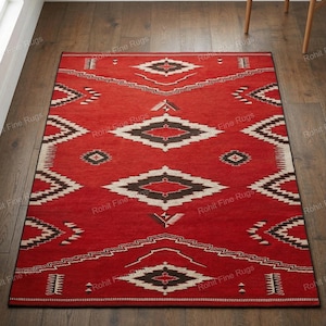 Può includere: Un tappeto rettangolare rosso con un motivo geometrico. Il tappeto presenta disegni a rombi e a zig-zag in bianco e nero. Il tappeto è posato su un pavimento in legno.