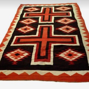 Pode incluir: Um tapete Navajo com um design tradicional que apresenta duas cruzes vermelhas sobre um fundo branco. O tapete tem uma borda preta e vermelha com um padrão geométrico.
