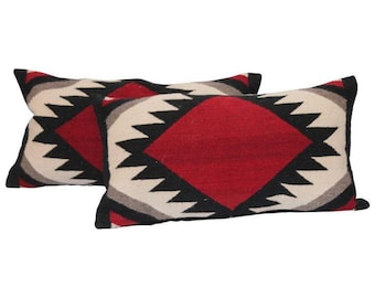 May include: Two rectangular pillows with a geometric pattern in black, white, red, and gray. The pattern features a large diamond shape in the center of each pillow.
