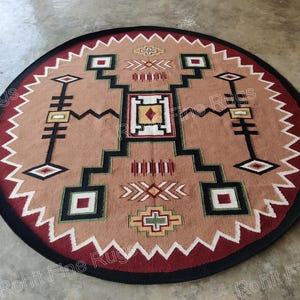 Puede incluir: Una alfombra redonda con un patrón geométrico en tonos de rojo, marrón, negro, blanco y verde. La alfombra tiene un borde negro y una franja alrededor del borde.