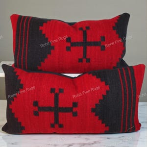 May include: Two rectangular throw pillows with a red and black geometric design. The pillows feature a central black cross motif and black borders. The text "Rohit Fine Rugs" is visible on the pillows.