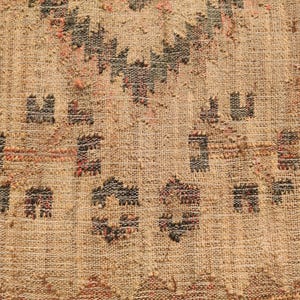 Puede incluir: Primer plano de un textil tejido con fondo beige y patrones geom&eacute;tricos en negro, rojo y marr&oacute;n. La textura parece &aacute;spera y natural, con nudos visibles y variaciones en el tejido.