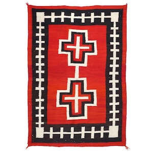 May include: A rectangular woven rug with a red central field. Two white and black crosses are centered on the rug. The rug is bordered by a black and white geometric pattern. The rug is likely made of wool.