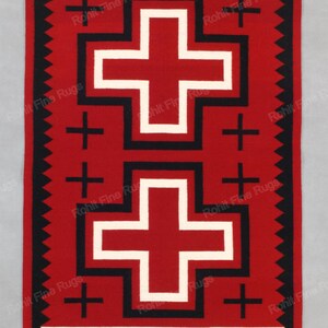 Op de afbeelding: Een rechthoekig rood tapijt met twee grote witte kruisen met zwarte omtrek. Het tapijt heeft een zwarte rand en een witte streep aan de bovenkant. Kleine zwarte kruisen zijn rond de grotere kruisen geplaatst. Traditioneel ontwerp.