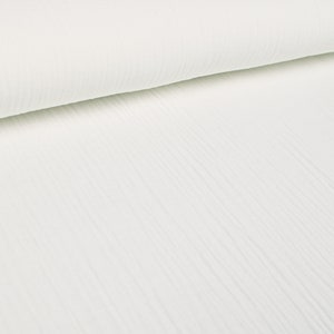 Può includere: Tessuto di cotone bianco con una texture stropicciata. Il tessuto è piegato a metà, mostrando la texture su entrambi i lati.