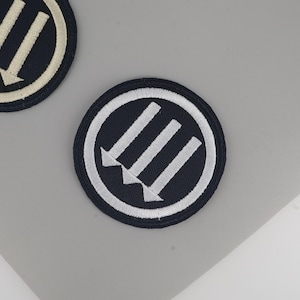 Broderad lapp med tre pilar, punkrock-stryk-på-applikation mot antifascistisk symbol