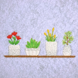 May include: Embroidered artwork featuring four potted plants on a brown shelf. The plants include red flowers, green succulents, yellow flowers, and a small green tree. The pots are white and the background is a light gray.