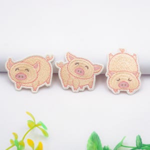 Può includere: Tre toppe ricamate da stirare con disegni di maiali rosa. I maiali sorridono e hanno gli occhi chiusi. Le toppe sono perfette per aggiungere un tocco di fantasia a vestiti, borse o altri oggetti in tessuto.
